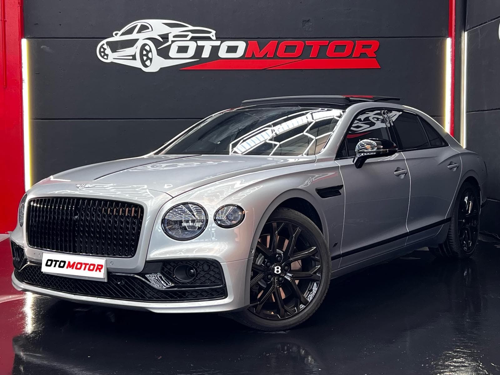 Bentley Flying Spur Hybrid gris metalizado, vista frontal en showroom OtoMotor